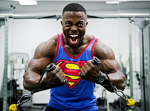 man wearing Superman tanktop puling weight exerciser
