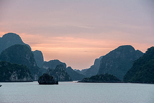 landscape photography of rocky island and ocean under cloudy sky, ha long bay, vietnam
