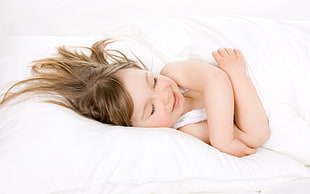 girl sleeping on bed with white bedspread and blanket