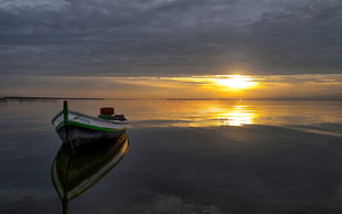 white boat on calm water during sunset