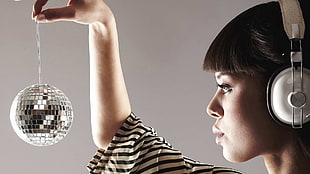 woman wearing headphones and holding reflecting disco ball