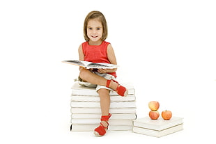 girl in red crew-neck sleeveless dress reading a book