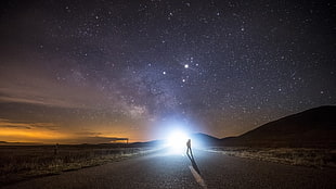 landscape photo of person standing in the middle of the road during starry night