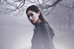 photo of woman wearing black leather jacket with tree and fog background