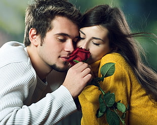 man and woman holding red Rose flower