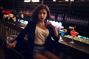 woman black cardigan and white scoop-neck top with blue denim short shorts outfit sitting on black leather bar stool
