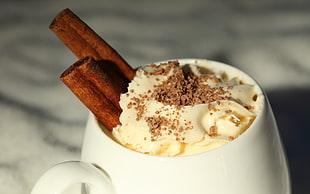 white bowl with cream and two cinnamon sticks