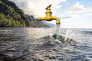yellow faucet opened on seawater near hill mountain filled with tree during day time HD wallpaper