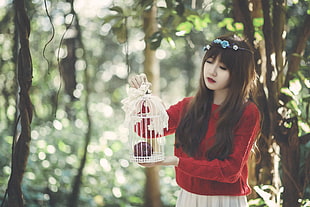 woman in red sweater holding white bird cage