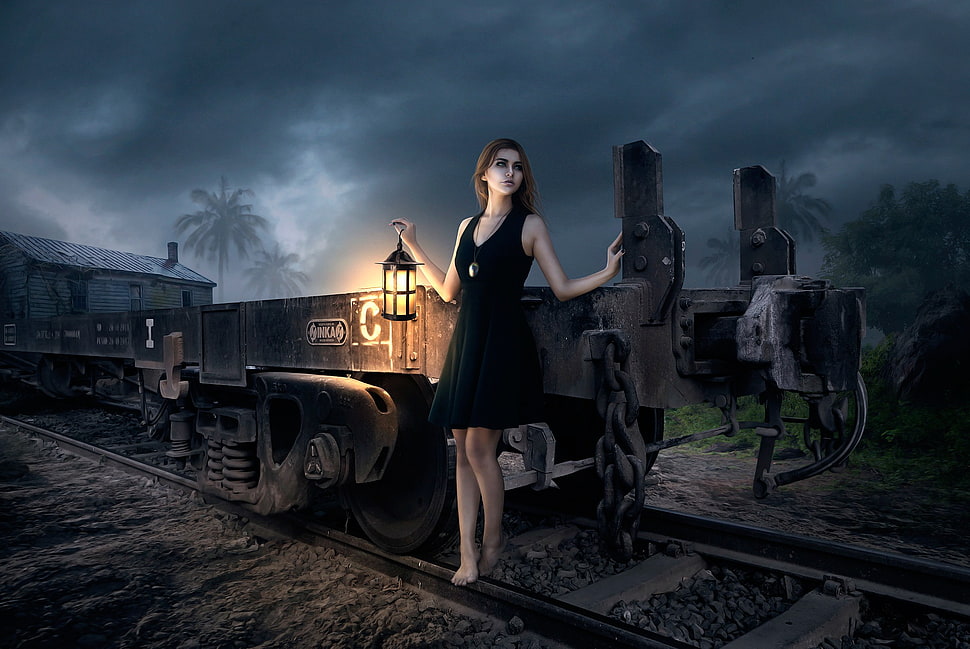 painting of woman wearing black sleeveless mini dress holding lantern near black train on rail HD wallpaper