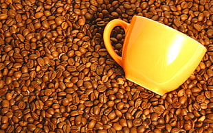 orange ceramic mug on coffee beans