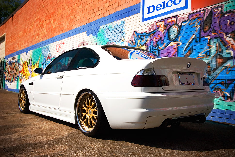 white BMW coupe parked near graffiti painted wall HD wallpaper
