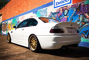 white BMW coupe parked near graffiti painted wall