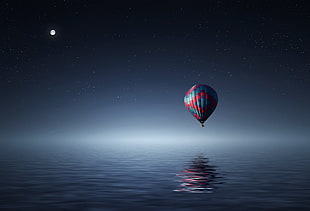 blue and red hot air balloon above body of water