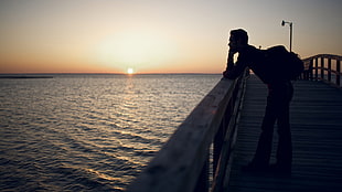 silhouette photography of man on sea dock photography HD wallpaper