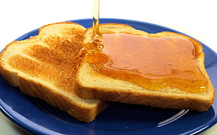 two toasted breads with honey on blue ceramic plate