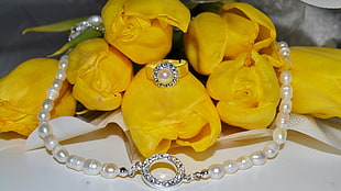 white pearl necklace and yellow petaled flowers