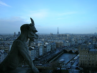 Gargoyle statuette on the top of the building during night time