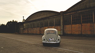 tan Volkswagen Beetle parked in front of brown dome roofed building