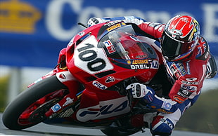 man in red and white racing suit riding sports motorcycle at daytime