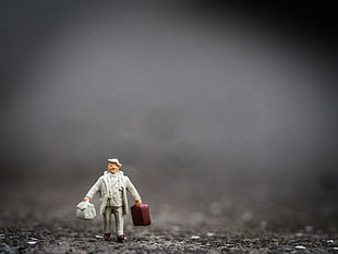 selective focus photography of a man holding two suitcases figurine