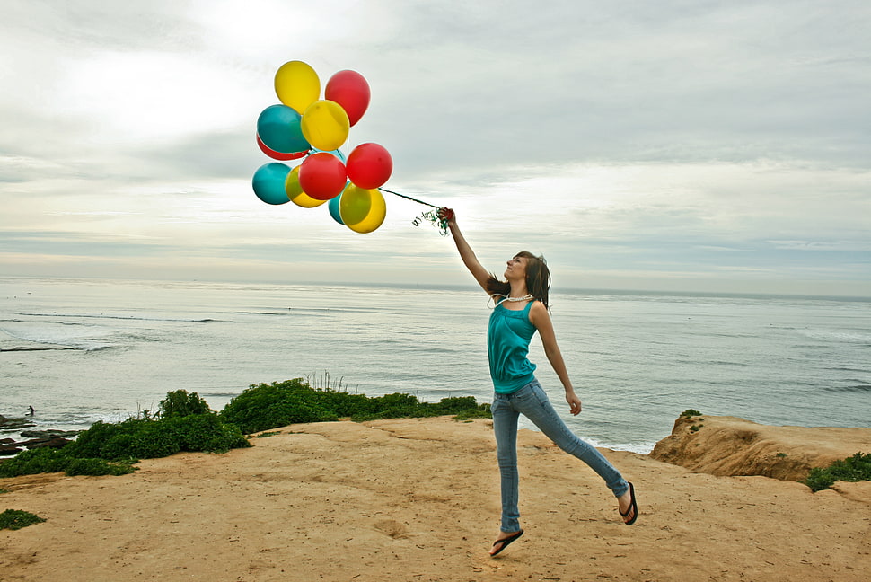 woman with blue tank top carrying a balloon near sea under blue sky HD wallpaper