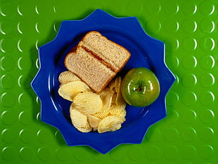 sliced bread, potato chips, and green apple on top of blue plate