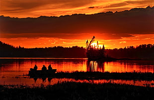 silhouette photo of 3 people riding on fish boat on near grasses during sun set