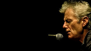 man wearing black shirt in front of microphone