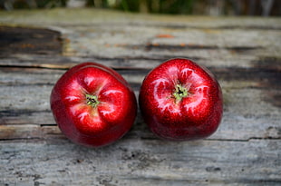 two red fruits placed on gray wooden board in focus photography