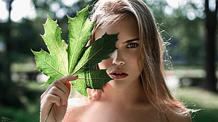 woman holds green maple leaf