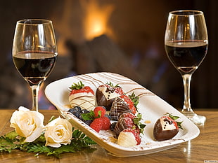 strawberries and chocolates at the plate between wine glasses filled with wines