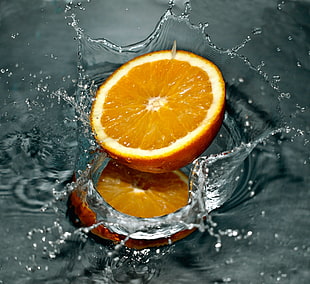 photo of sliced orange fruit splashed on water