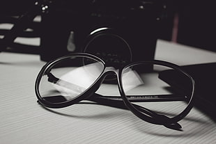 black framed eyeglasses beside black bridge camera