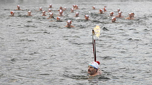 group of people swimming on body of water while wearing red swimming caps
