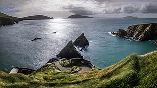 green grass and blue sea around rock formation, dunquin, kerry, ireland