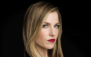 woman in serious face wearing red lipstick and black mascara with black background