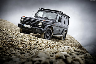 black Mercedes-Benz SUV on brown soil with stones