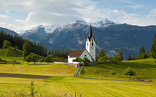 white and brown concrete buildings, church, grass, mountains