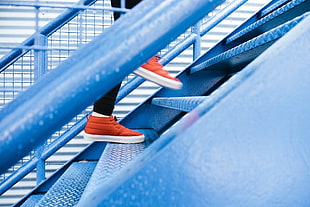 person in orange-and-white low-top sneakers walking on stairs at daytime