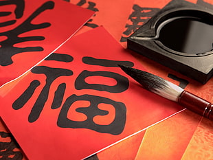photography of kanji calligraphy beside paint brush