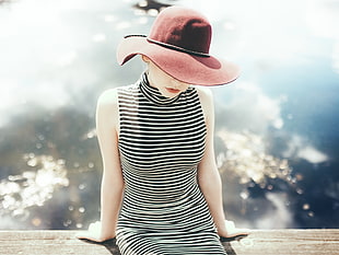 selective focus photography of woman in black and white striped sleeveless dress and red hat