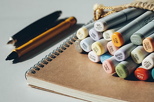 assorted pen marker lot on top of spring notebook HD wallpaper
