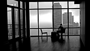 grayscale photo of person near window, urban