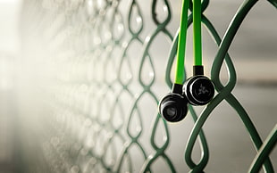 green earphones hanged on cyclone fence