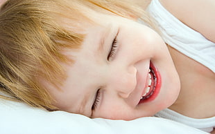 toddler in white tank top lying on bed