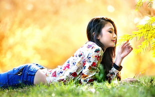 woman lying down on green grass field smelling leaves
