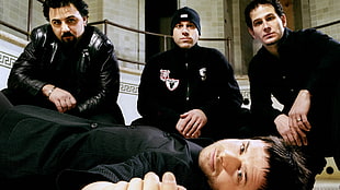 four men wearing black suit rock band