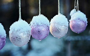 close view of four pink baubles covered with snow