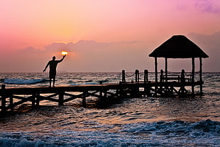 man standing on dock during sunset